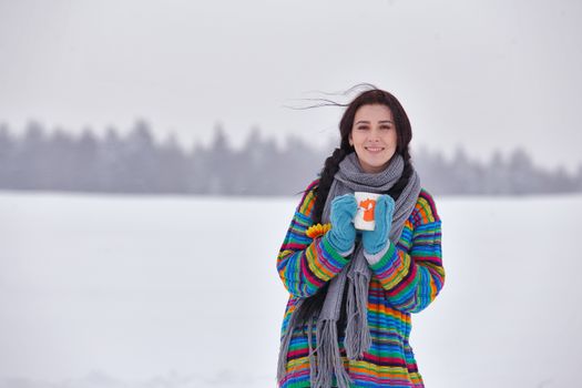 Beautiful girl in a sweater on a winter walk with a cup of tea