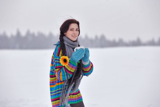 Beautiful girl in a sweater on a winter walk with a cup of tea