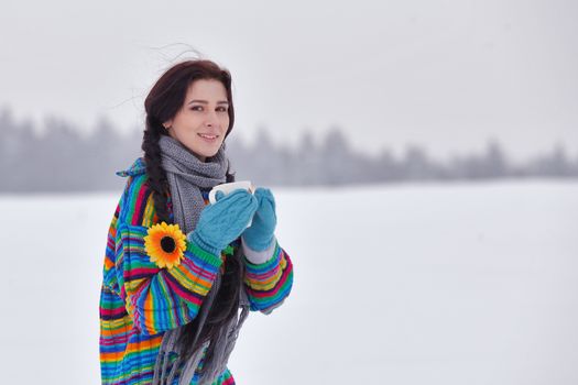 Beautiful girl in a sweater on a winter walk with a cup of coffee