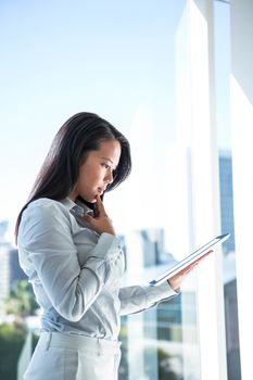 Thoughtful businesswoman using tablet outdoors