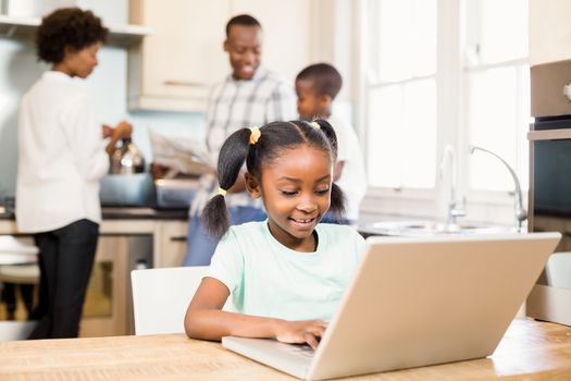 Daughter using laptop against parents in the kitchen