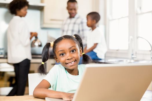 Daughter using laptop against parents in the kitchen