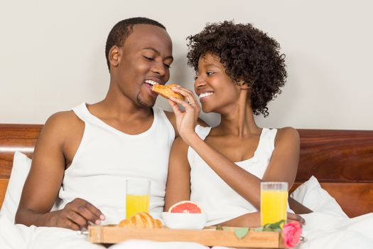 Happy family lying in bed together enjoying breakfast