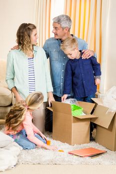 Portrait of happy family opening boxes in living room
