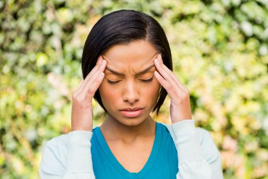 Portrait of frowning brunette with headache outdoors