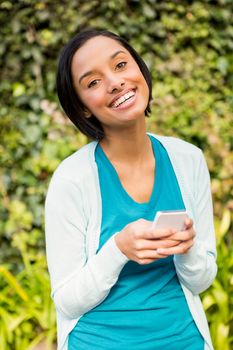 Happy brunette using smartphone outdoors