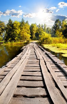 Bridge through river in sunny autumn day