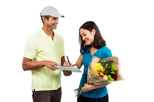 Woman signing on clipboard while receiving bouquet against white background 