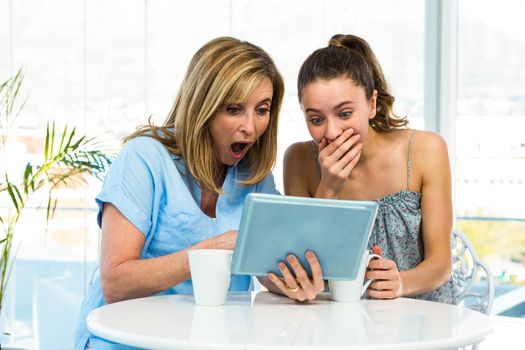 Mother and daughter watch tablet in the kitchen