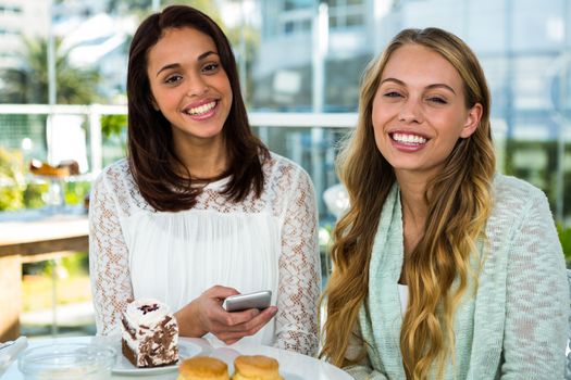 two girls watch use phone while eating