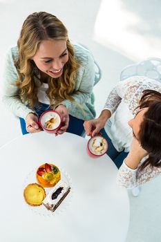 two girls drink coffee and eating pastries