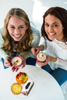 two girls drink coffee and eating pastries