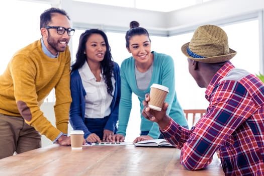 Cheerful young business people discussing with each other at creative office