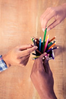 Business people choosing pencils from container in creative office
