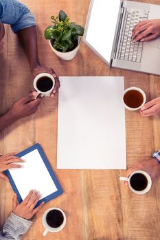 Business people using technologies while holding coffee cups at desk