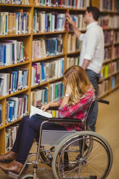Student in wheelchair talking with classmate in library