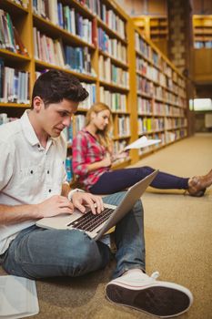 Concentrated students working on floor in library