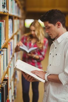 Concentrated male student reading book in library