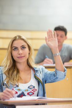 Attractive student raising hand during class at the lecture hall