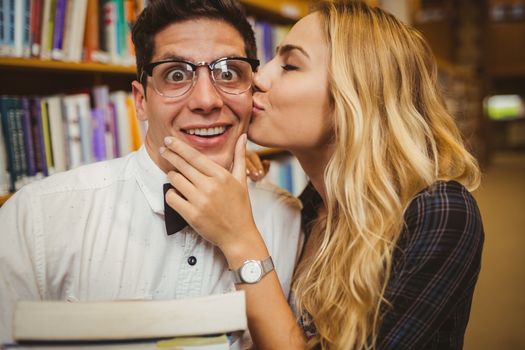 Nerd getting kissed by pretty girl in library