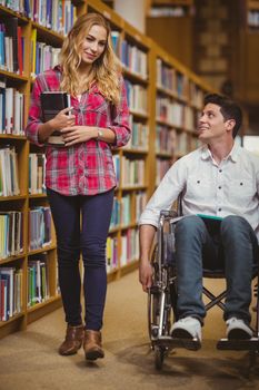 Student in wheelchair talking with classmate in library