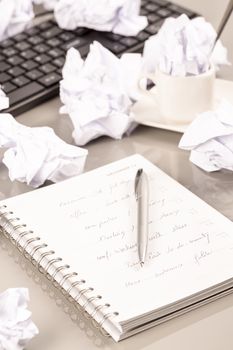 Office workplace with book, crumpled paper, pen,  on grey desk