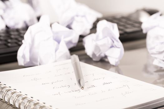 Office workplace with book, crumpled paper, pen,  on grey desk