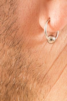 pierced ear of a mature man close-up short beard