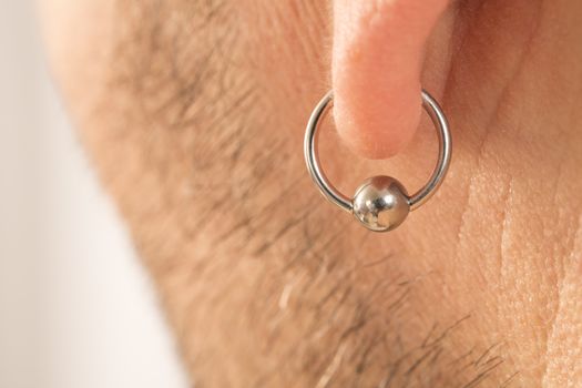 pierced ear of a mature man close-up short beard