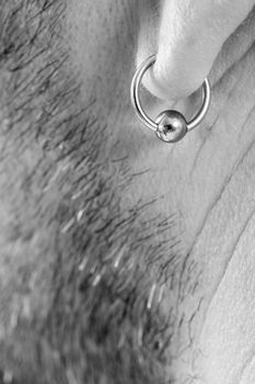 pierced ear of a mature man close-up short beard