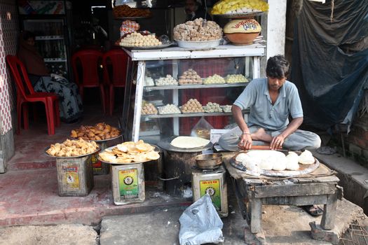 Vendor sits in lotus position while sells goods in Indian shop. January 17, 2009. Sonakhali, West Bengal, India.