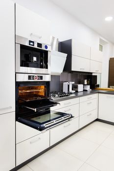 Modern luxury hi-tek black and white kitchen, clean interior design, focu at oven with door open