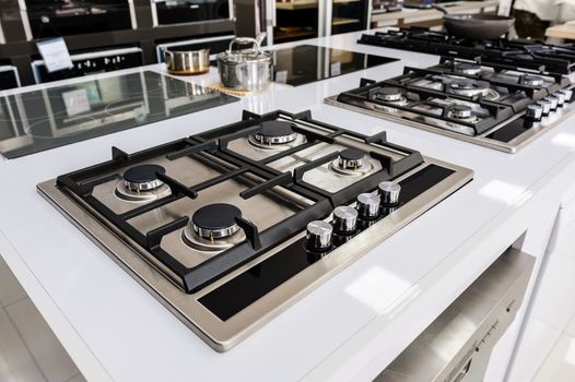 Rows of gas stoves with stainless tray selling in appliance retail store