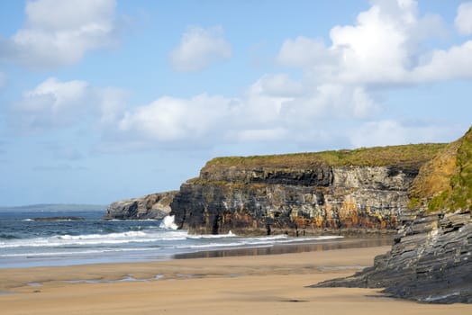 beautiful waves break on the beach cliffs at ballybunion