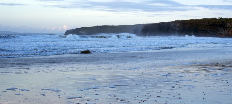 winter waves crashing onto the beach cliffs at ballybunion