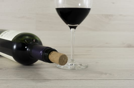 bottle red wine and glass on wooden background