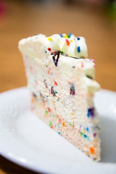 A small slice of confetti vanilla birthday cake on a white plate