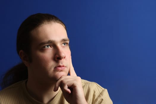 Long hair man thinking and looking to right upper corner (place for sign)