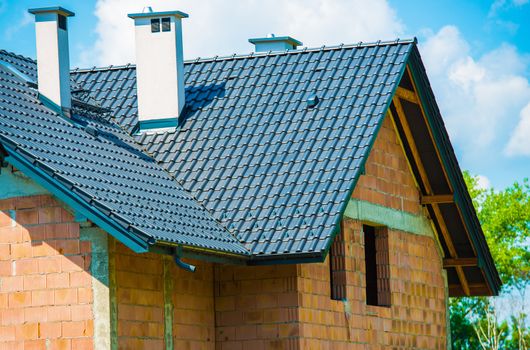 European Style Brick House Under Construction. Closeup Photo of Dark Ceramic Roof.