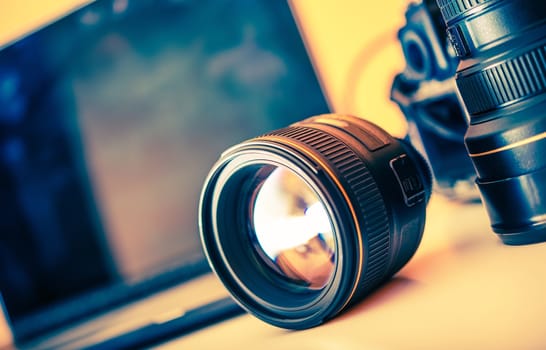 Photographer Desk with Lenses and Laptop Computer in the Background. Photography Theme.