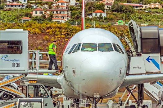 Funchal, Madeira, Portugal - May 30, 2013: At the airport of Madeira (Aeroporto Madeira) - an airplane Airbus A320 from TAP Portugal Airline in parking position. Ground force stuff at work.