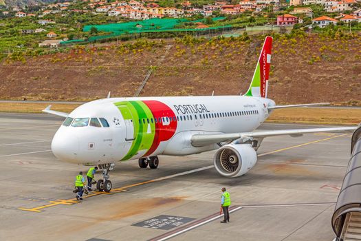 Funchal, Madeira, Portugal - May 30, 2013: At the airport of Madeira (Aeroporto Madeira) - an airplane Airbus A320 from TAP Portugal Airline in parking position. Ground force stuff aside.