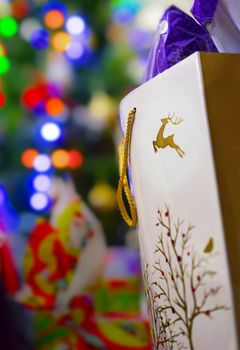 Bright Christmas celebration background with lights, gift bag, presents and tree with bokeh