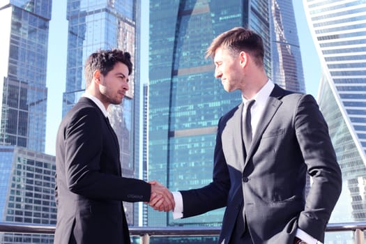 Business people shaking hands on skyscraper background