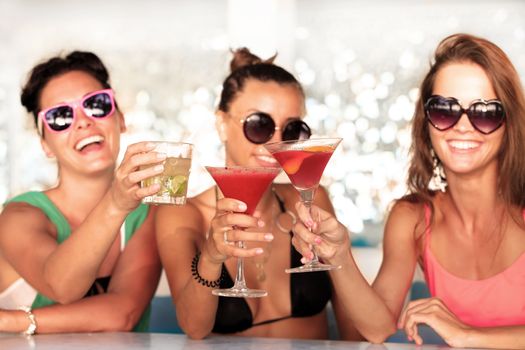 Happy young women with beverages having fun in cafe