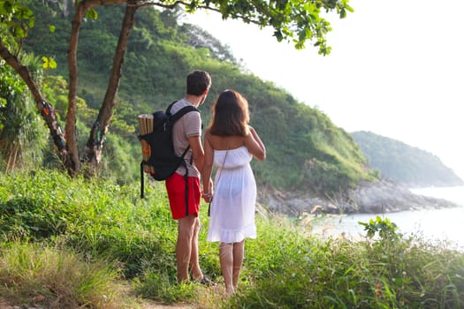 Two hikers  standing on hiil and looking at sea