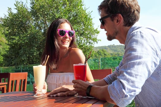 Happy couple enjoy their cocktails in outdoor cafe