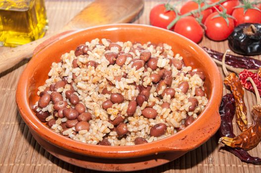 Casserole of beans with rice and various ingredients on a tablecloth raffia