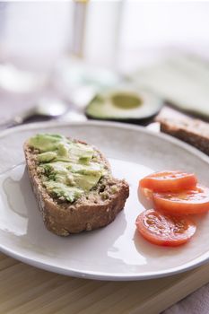Fresh avocado on thick sliced whole wheat bread with tomatoes.