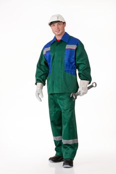 Young man in the uniform on isolated background holding a big wrench
